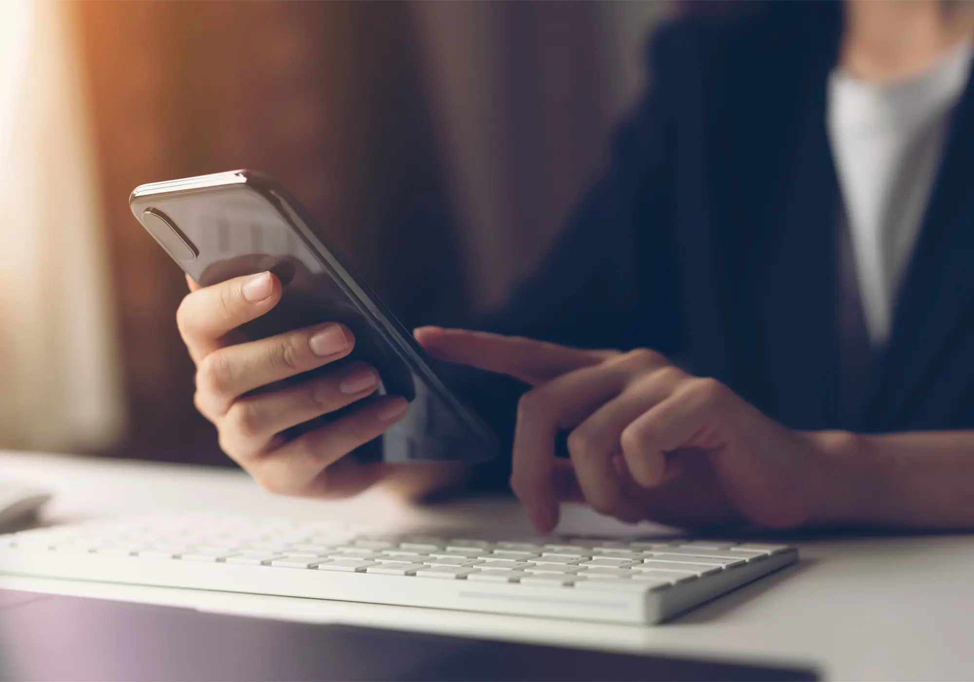 Woman sitting at her computer, banking on her mobile device